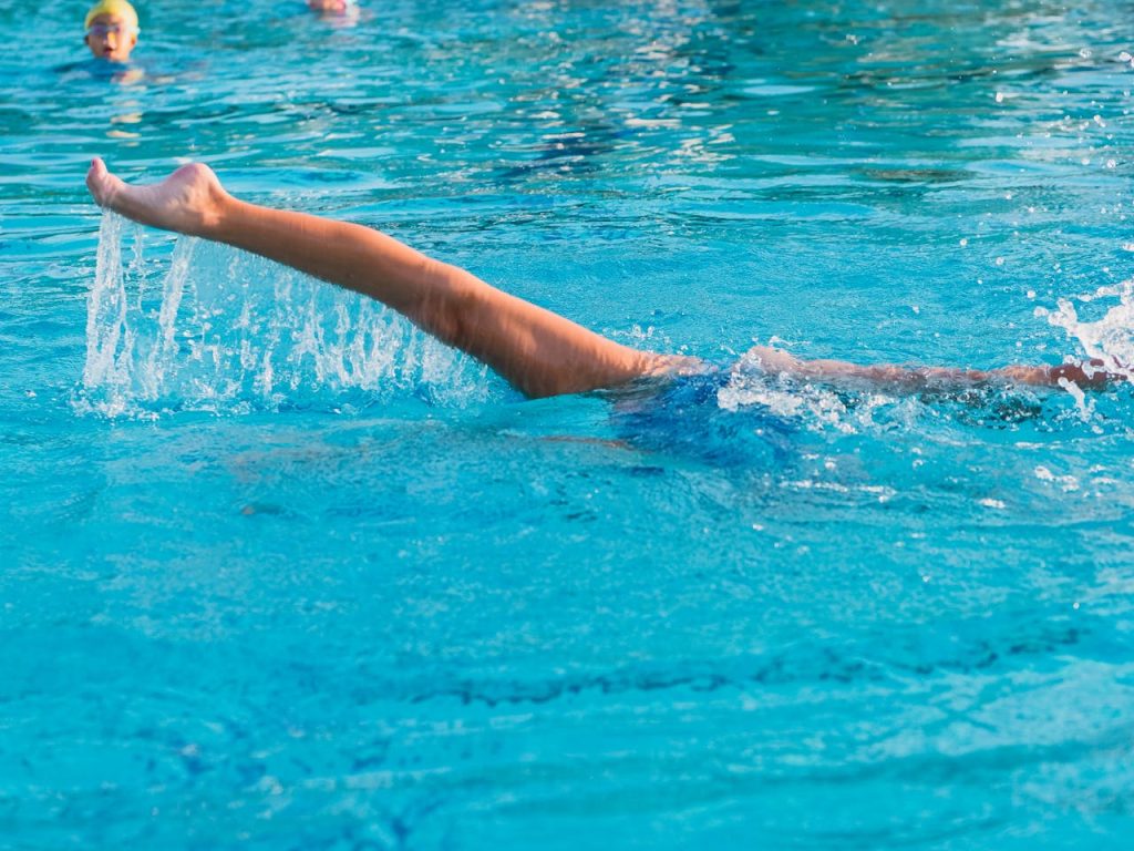 Dynamic shot of a swimmers arm slicing through the water in a clear blue swimming pool.